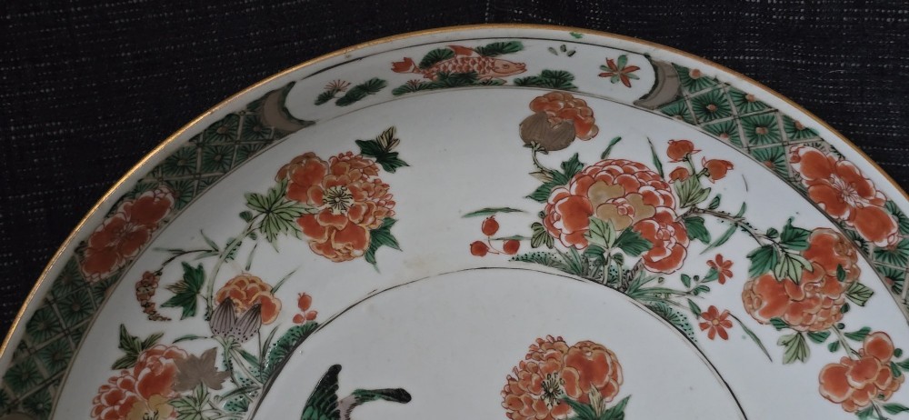 A circular Chinese famille verte porcelain dish featuring hand-painted peony blossoms, foliage, a bird in flight, and a decorative patterned border. View VIII