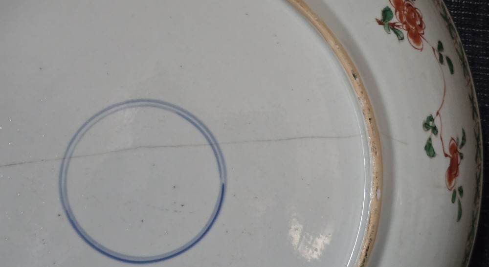 A circular Chinese famille verte porcelain dish featuring hand-painted peony blossoms, foliage, a bird in flight, and a decorative patterned border. View IX