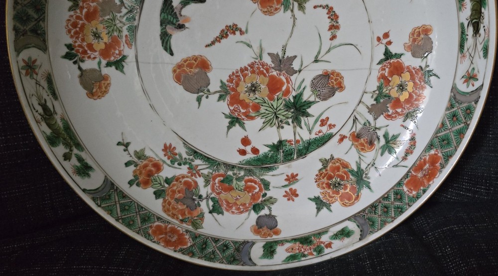 A circular Chinese famille verte porcelain dish featuring hand-painted peony blossoms, foliage, a bird in flight, and a decorative patterned border. View XI