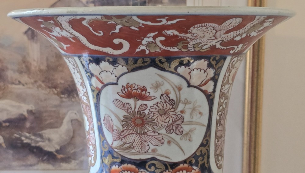 A tall Japanese Imari porcelain trumpet vase featuring hand-painted designs of horses, floral panels, and geometric borders in blue, iron red, and enamels. View VI