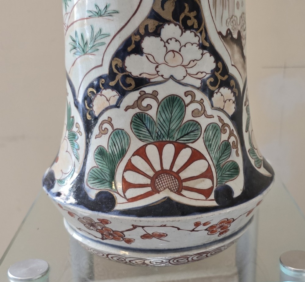 A tall Japanese Imari porcelain trumpet vase featuring hand-painted designs of horses, floral panels, and geometric borders in blue, iron red, and enamels. View X
