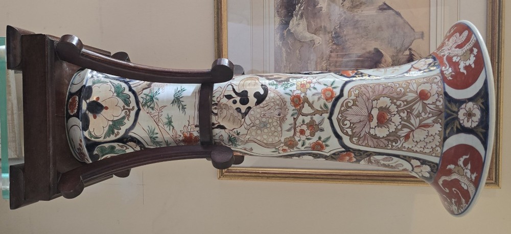 A tall Japanese Imari porcelain trumpet vase featuring hand-painted designs of horses, floral panels, and geometric borders in blue, iron red, and enamels. View XIV