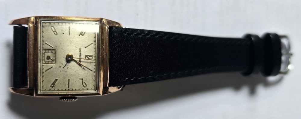 A vintage Longines rectangular wristwatch featuring a rose gold-filled case, patinated dial with Arabic numerals, sub-seconds register, and a black leather strap. View IV