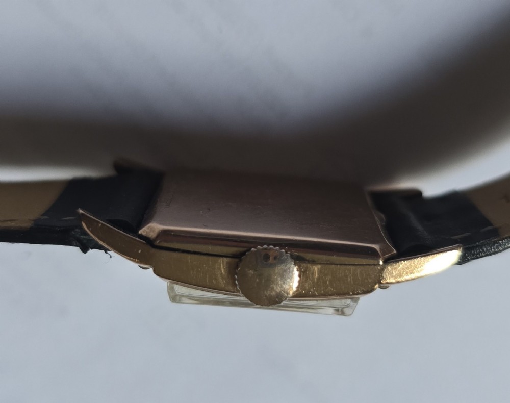 A vintage Longines rectangular wristwatch featuring a rose gold-filled case, patinated dial with Arabic numerals, sub-seconds register, and a black leather strap. View V