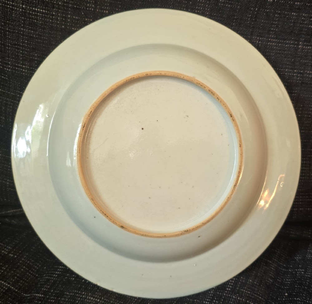 A circular Chinese export porcelain plate featuring a central heraldic crest with red mantling, encircled by a geometric diaper border and floral sprigs. View X