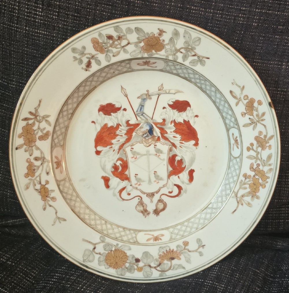 A circular Chinese export porcelain plate featuring a central heraldic crest with red mantling, encircled by a geometric diaper border and floral sprigs. View XV