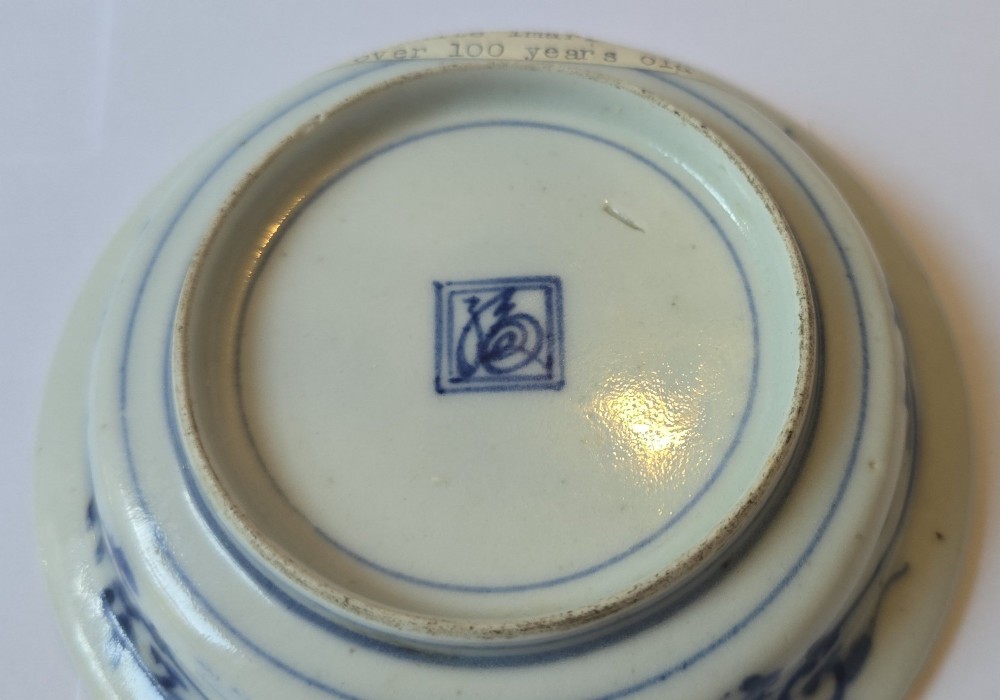 A circular Edo period Japanese Arita porcelain shallow dish featuring hand-painted cobalt blue underglaze figurative and floral decoration on an off-white ceramic body. View VII
