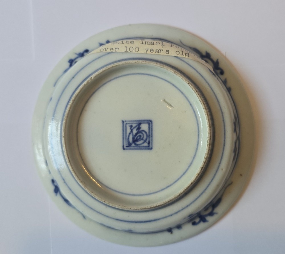 A circular Edo period Japanese Arita porcelain shallow dish featuring hand-painted cobalt blue underglaze figurative and floral decoration on an off-white ceramic body. View XII