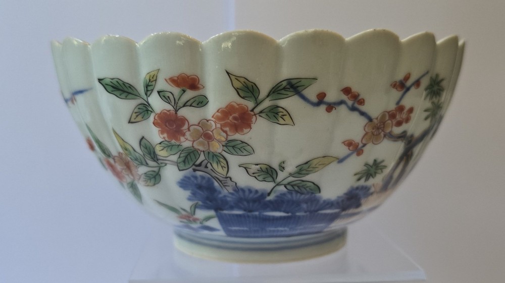 A fluted late 17th-century Japanese porcelain bowl decorated with polychrome floral enamel motifs against an off-white background.