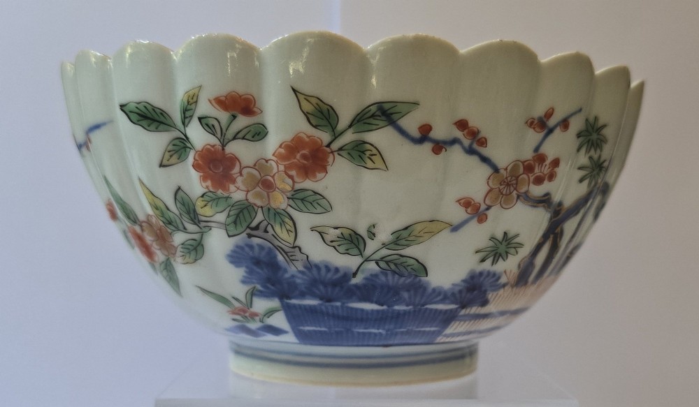 A fluted late 17th-century Japanese porcelain bowl decorated with polychrome floral enamel motifs against an off-white background. View II