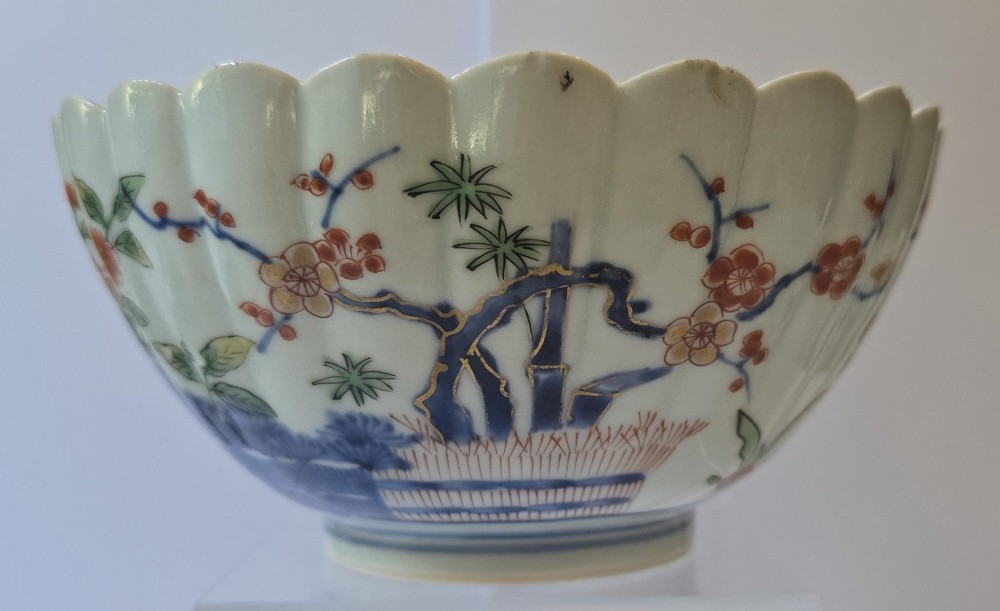 A fluted late 17th-century Japanese porcelain bowl decorated with polychrome floral enamel motifs against an off-white background. View III