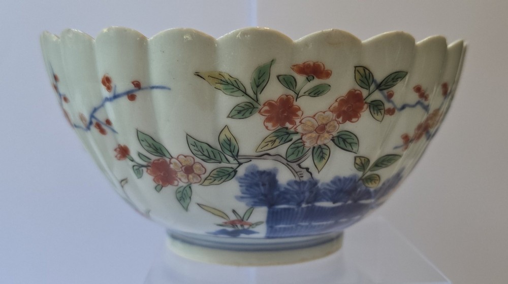 A fluted late 17th-century Japanese porcelain bowl decorated with polychrome floral enamel motifs against an off-white background. View V