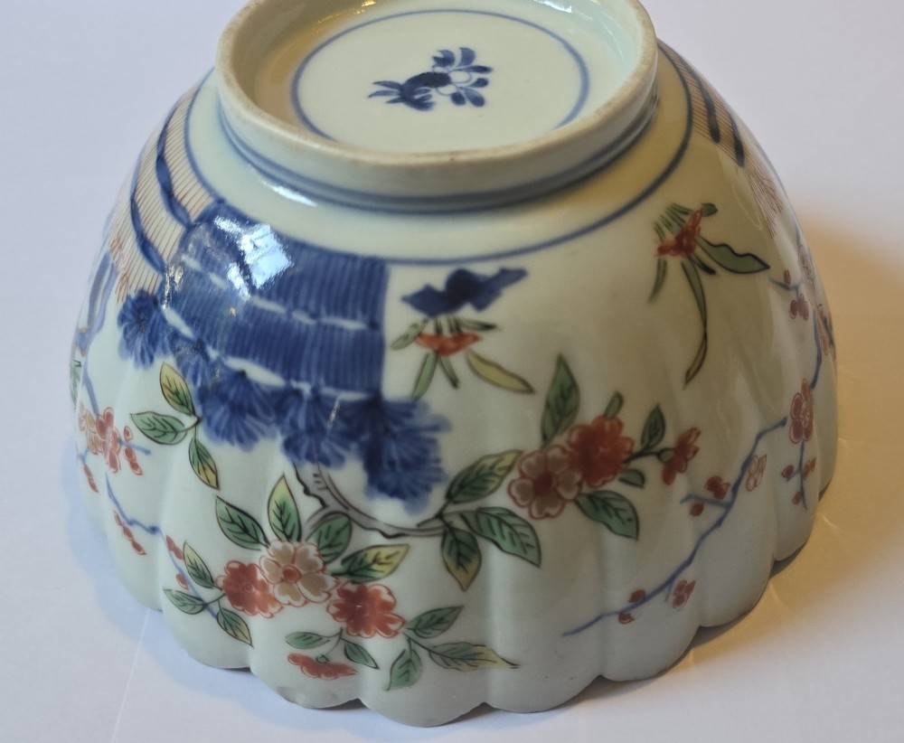 A fluted late 17th-century Japanese porcelain bowl decorated with polychrome floral enamel motifs against an off-white background. View VIII