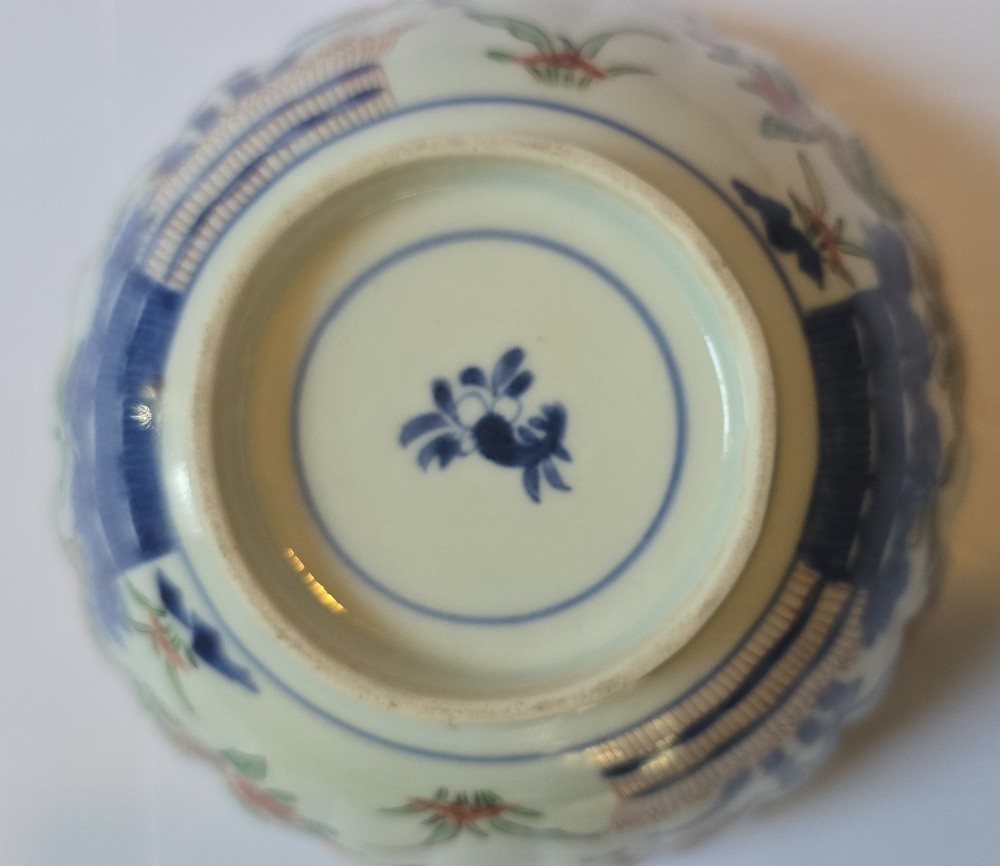 A fluted late 17th-century Japanese porcelain bowl decorated with polychrome floral enamel motifs against an off-white background. View X