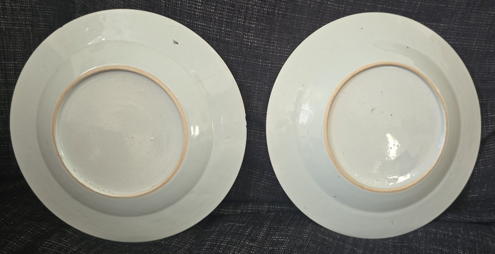 A pair of circular white porcelain plates hand-painted with famille rose enamels depicting figures in an interior and garden setting with a floral rim border. View III