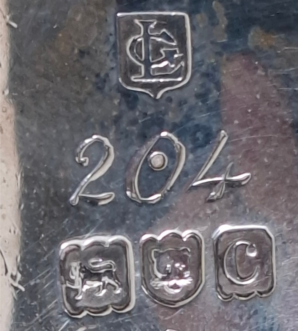 A Victorian sterling silver sauce boat featuring a scalloped rim, a double-scroll handle, and three shell-capped feet. View IX