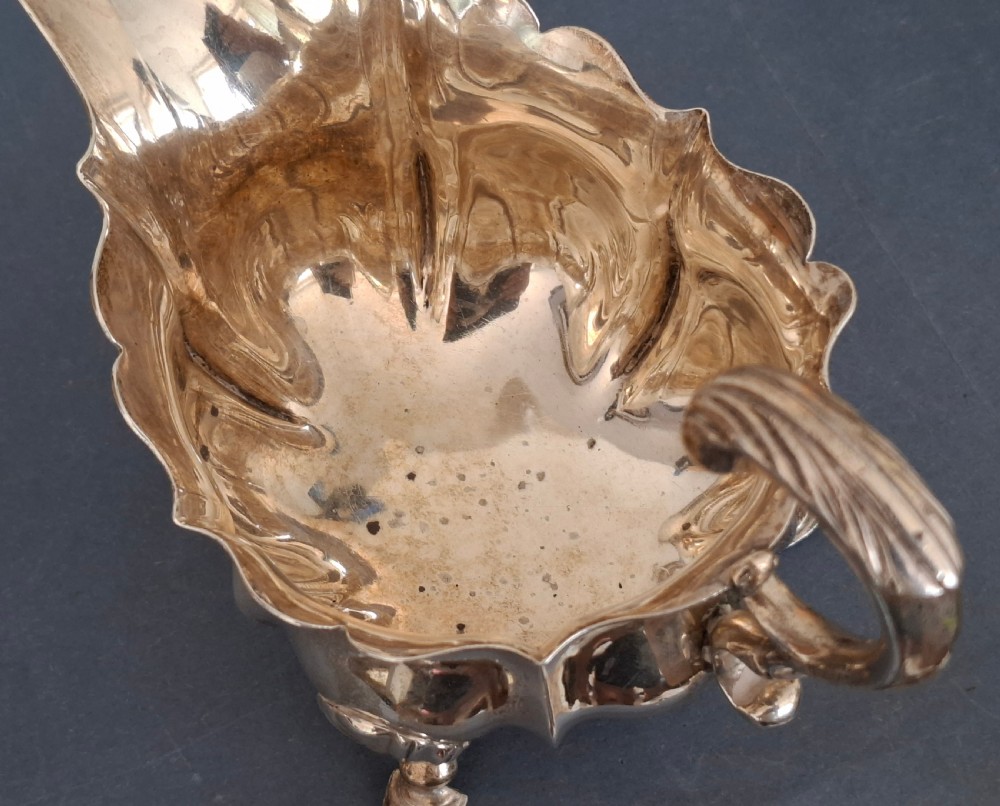 A collection of twenty-eight sterling silver tea and coffee spoons arranged in groups on a dark grey background. View X