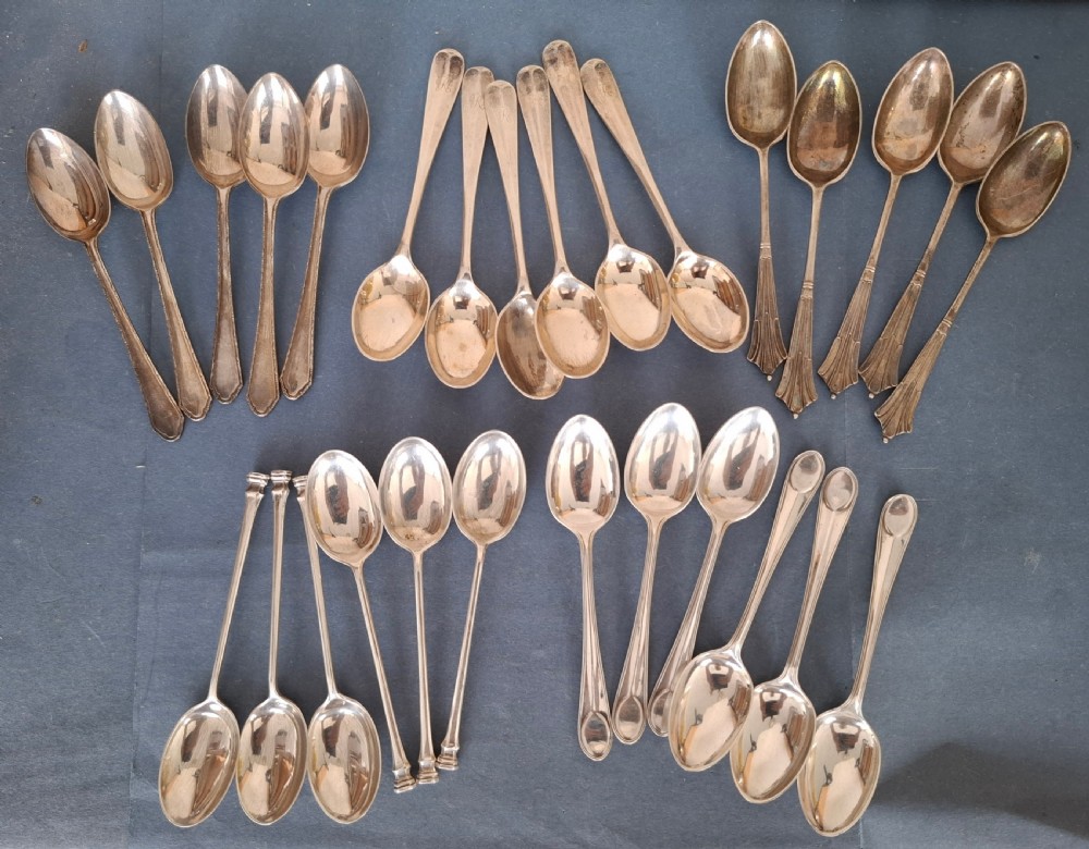 A collection of twenty-eight sterling silver tea and coffee spoons arranged in groups on a dark grey background. View II