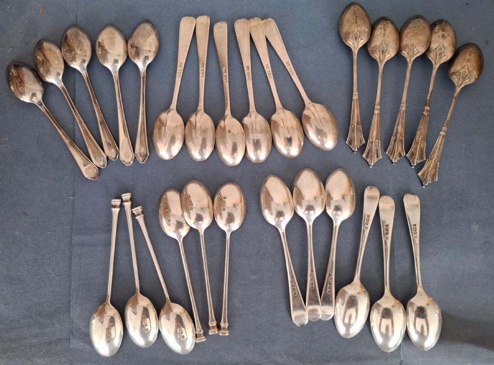 A collection of twenty-eight sterling silver tea and coffee spoons arranged in groups on a dark grey background. View III