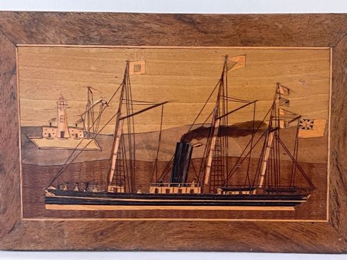 fig 1. A rectangular mahogany money box featuring an inlaid wooden marquetry panel depicting a steamship at sea alongside a lighthouse.