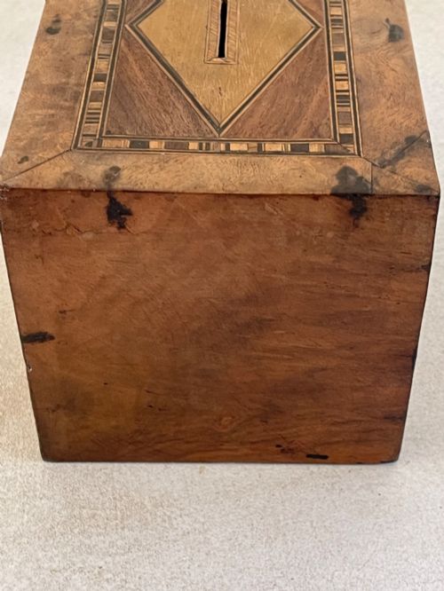 fig 2. A rectangular mahogany money box featuring an inlaid wooden marquetry panel depicting a steamship at sea alongside a lighthouse.