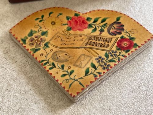 fig 1. An open small wooden box containing printed paper riddle slips set behind a heart-shaped printed card with floral motifs.