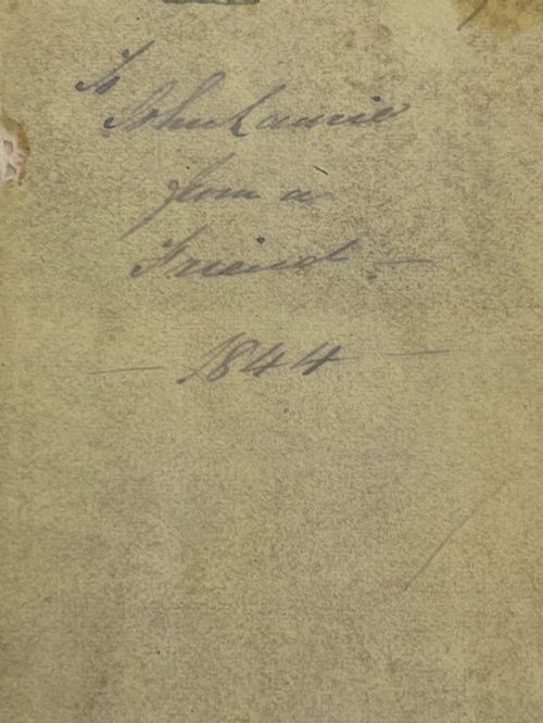 fig 1. An antique small volume bound with dark wooden board covers, a worn red spine with gilt lettering, and internal pages with printed maritime engravings.