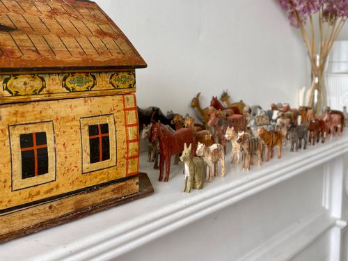fig 1. A hand-painted 19th-century wooden Noahs ark toy with a pitched roof and painted windows, accompanied by carved wooden figures.