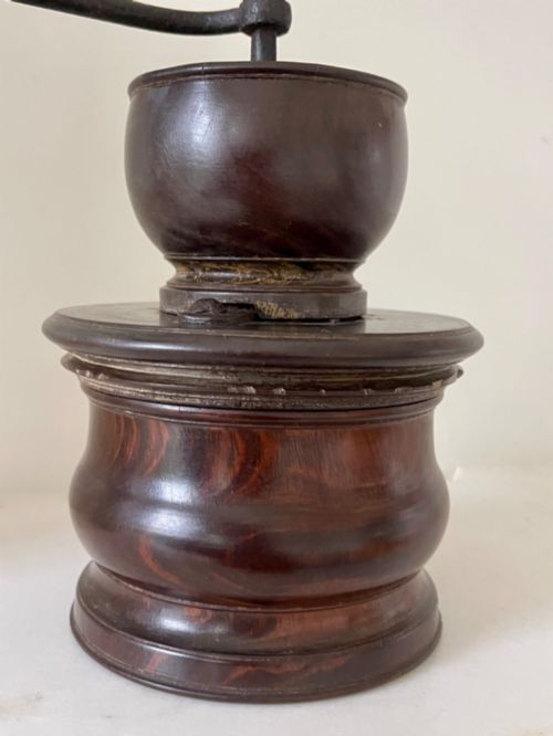 fig 1. A turned dark brown lignum vitae coffee grinder with a curved iron crank handle and turned wooden knob.