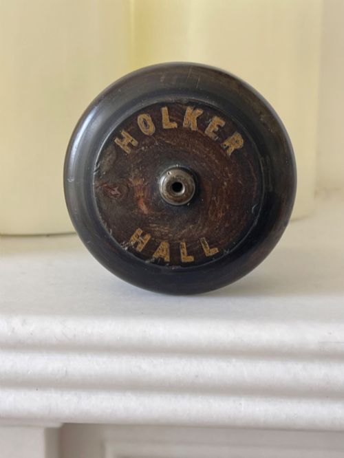 fig 2. A small turned dark wooden go-to-bed match holder featuring a cylindrical body, a moulded cap, and a match inserted in the centre top.