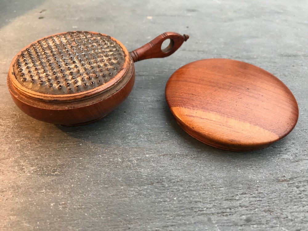 An unusual early 1800's cherry wood nutmeg grater in the shape of a saucepan