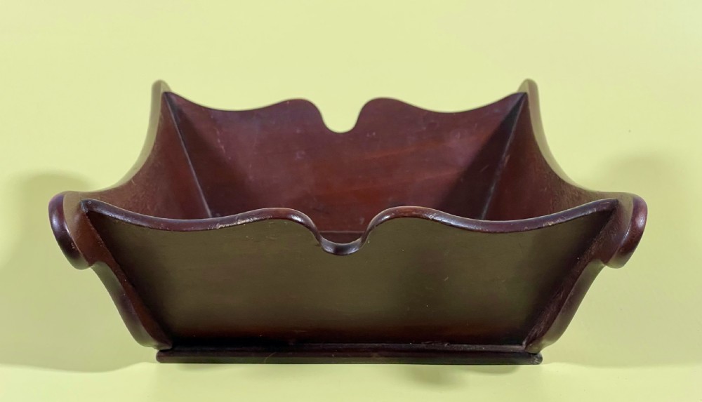 A Georgian mahogany deep wooden container featuring flared scalloped side rims and a rectangular base.