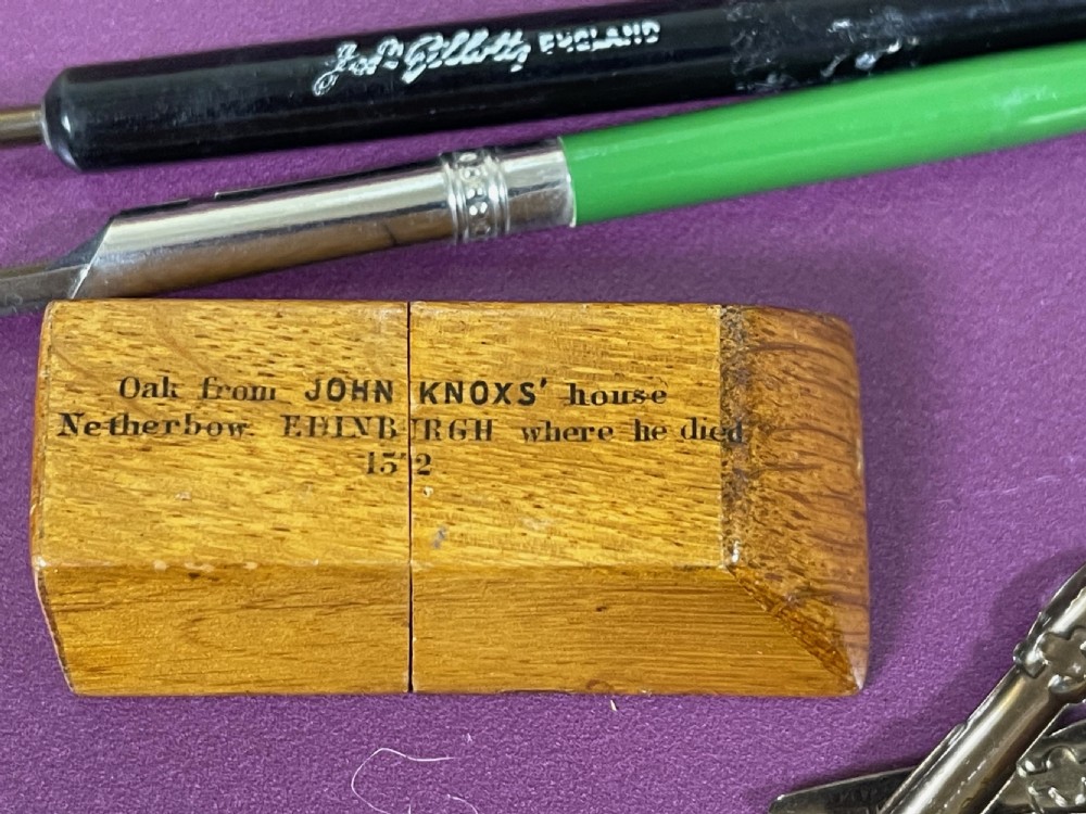 A small standing wooden oak nib box with a sloped top, bearing black printed text referencing John Knox on the front face. View IV