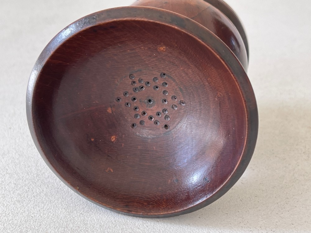 A turned dark fruitwood pounce pot featuring a perforated concave top dish above a bulbous stem and circular moulded base. View IV