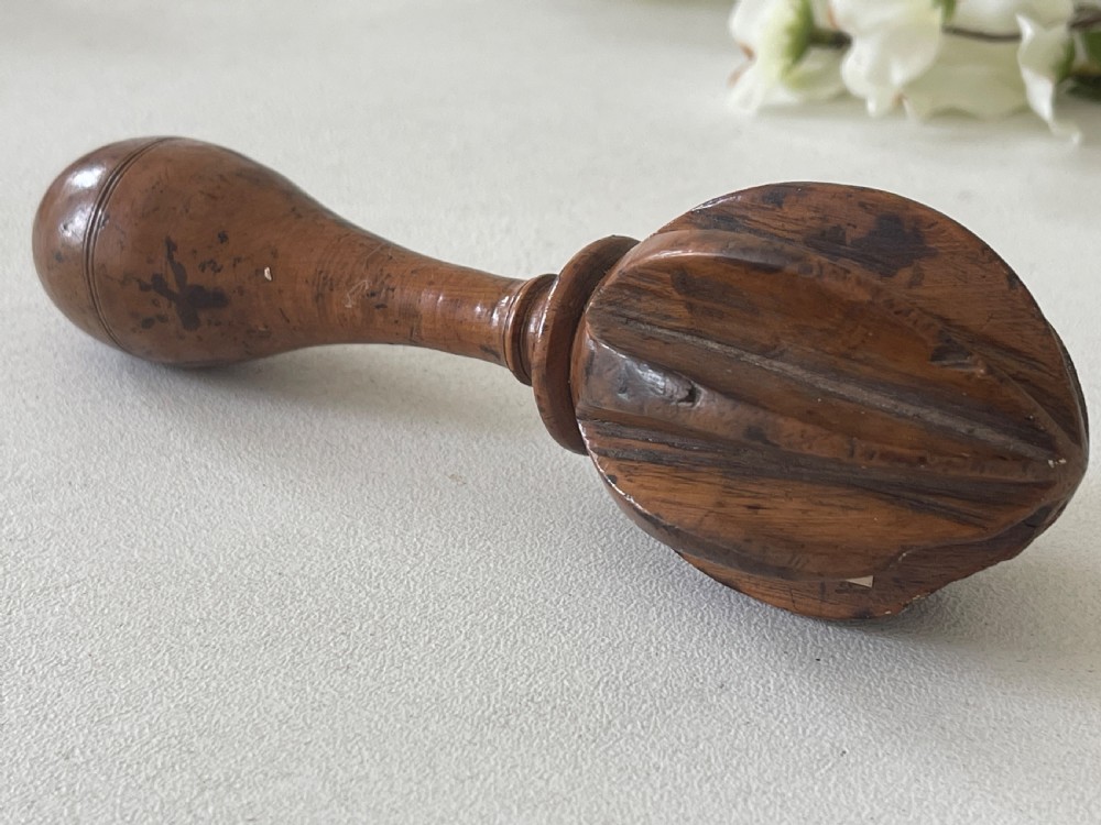 A turned wooden antique citrus reamer featuring carved reeded ribs and a rounded ergonomic handle with scored detail. View II