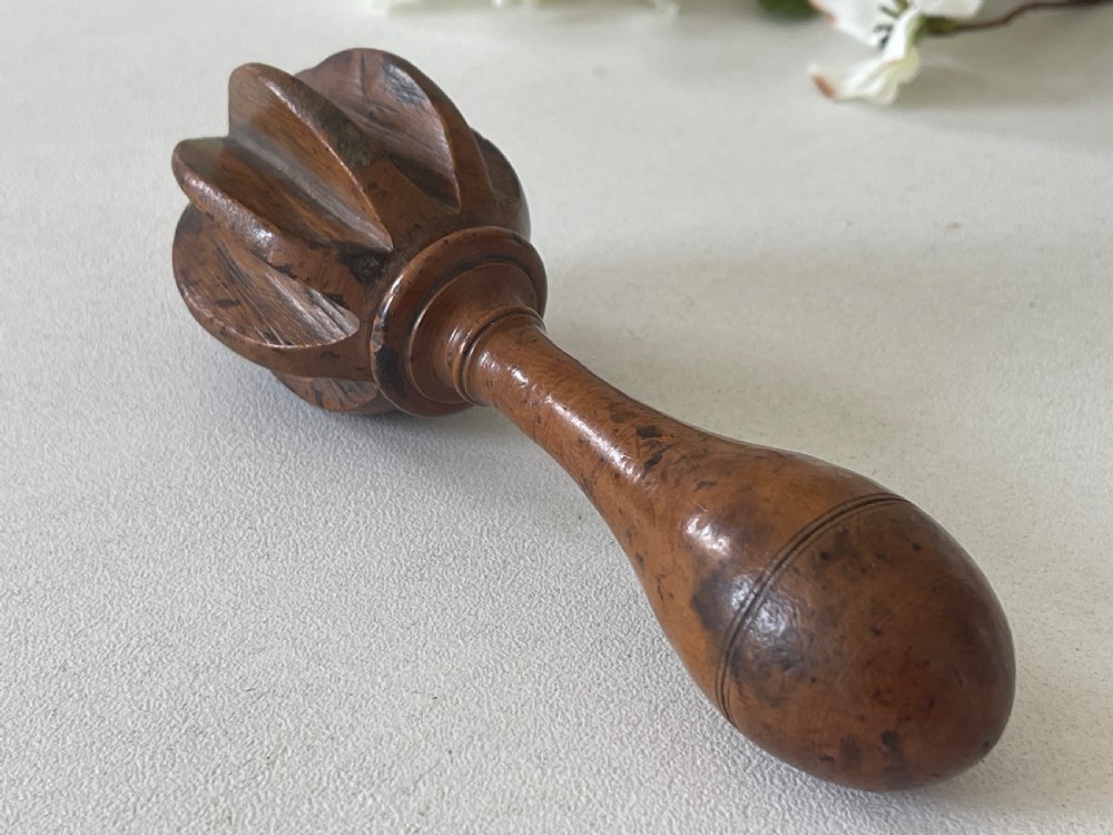 A turned wooden antique citrus reamer featuring carved reeded ribs and a rounded ergonomic handle with scored detail. View V