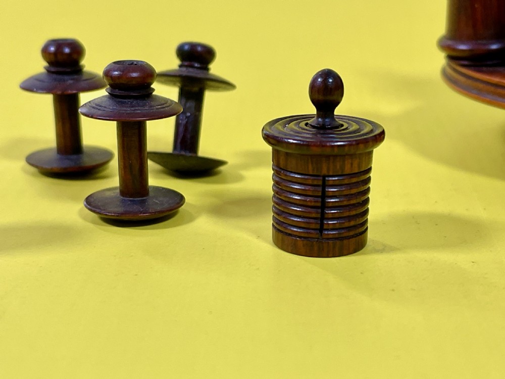 An antique turned rosewood sewing companion featuring a central turret-shaped spool holder surrounded by turned finials and sewing tools on a circular base with feet. View II