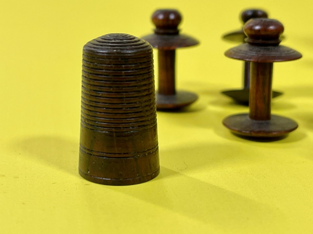 An antique turned rosewood sewing companion featuring a central turret-shaped spool holder surrounded by turned finials and sewing tools on a circular base with feet. View III