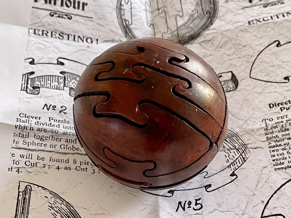 An early 1900's antique treen jigsaw in the shape of a wooden ball