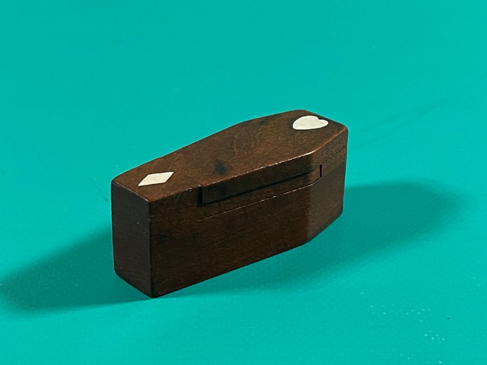 A small dark wood coffin-shaped antique snuff box featuring a swivelling lid with inlaid heart and diamond shapes. View III