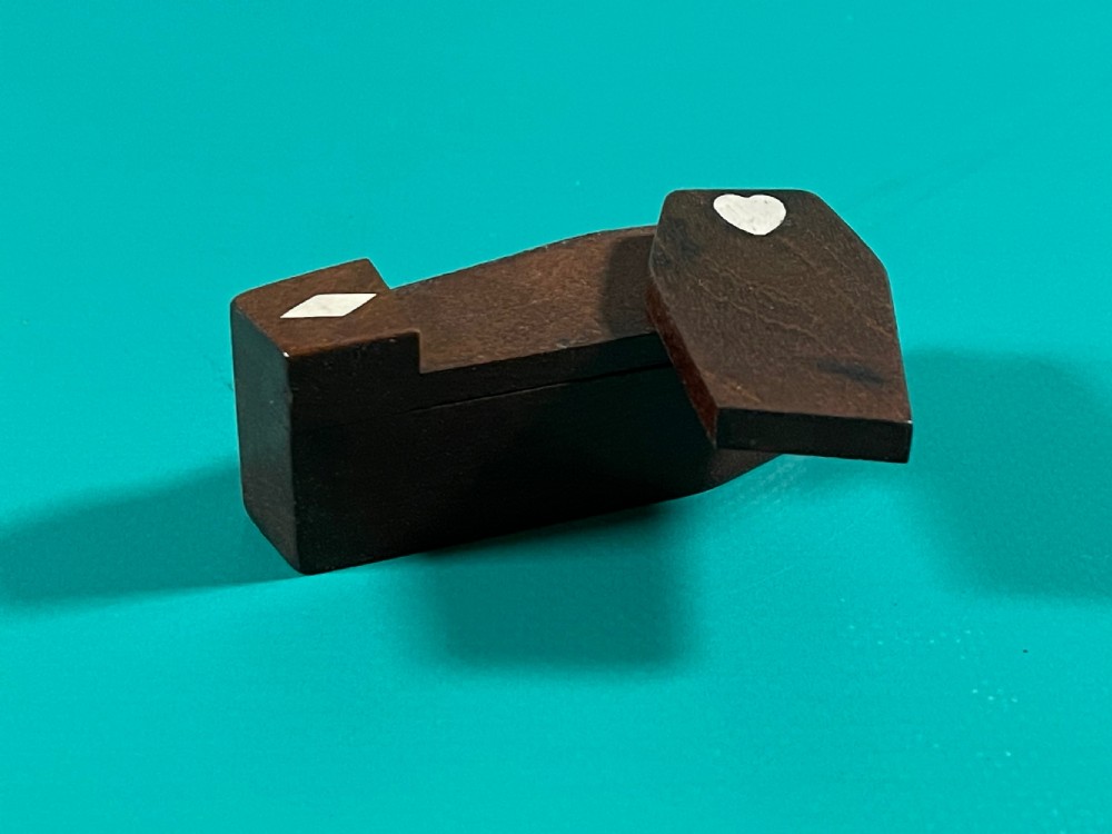 A small dark wood coffin-shaped antique snuff box featuring a swivelling lid with inlaid heart and diamond shapes. View IV