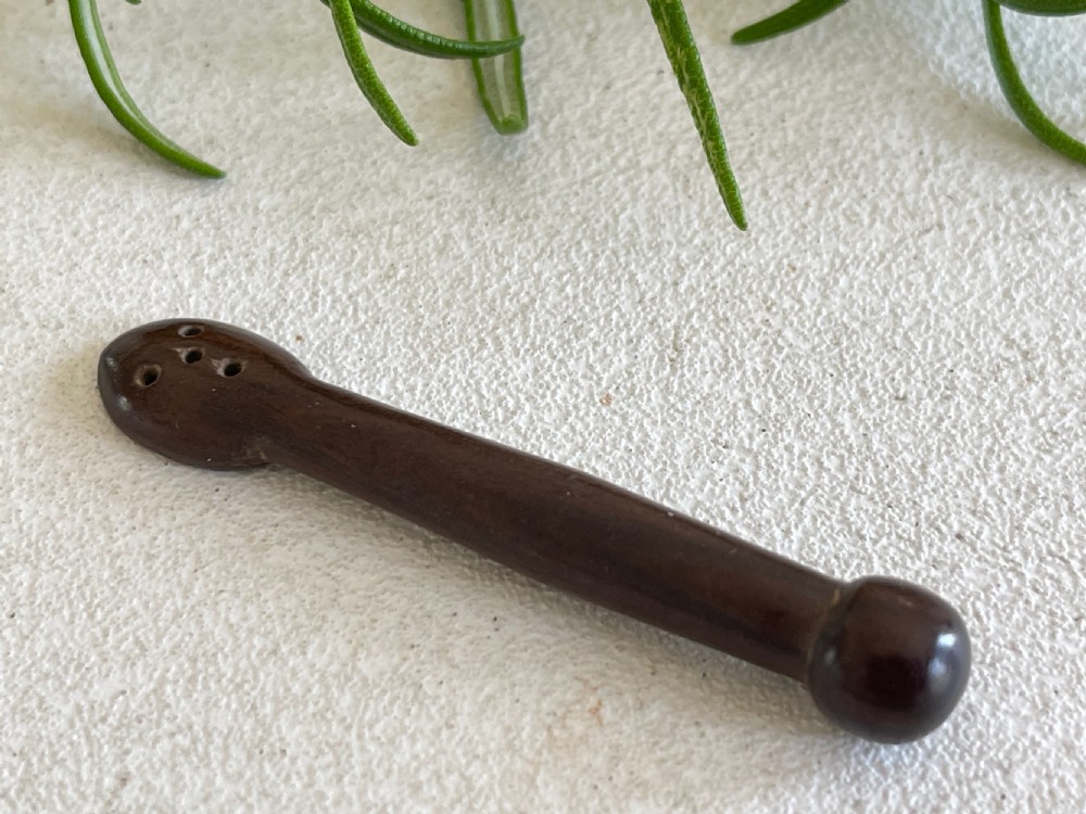 A dark carved wooden treen snuff spoon featuring a pierced bowl and a turned rounded terminal.