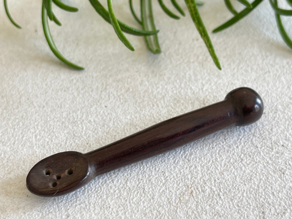 A dark carved wooden treen snuff spoon featuring a pierced bowl and a turned rounded terminal. View II