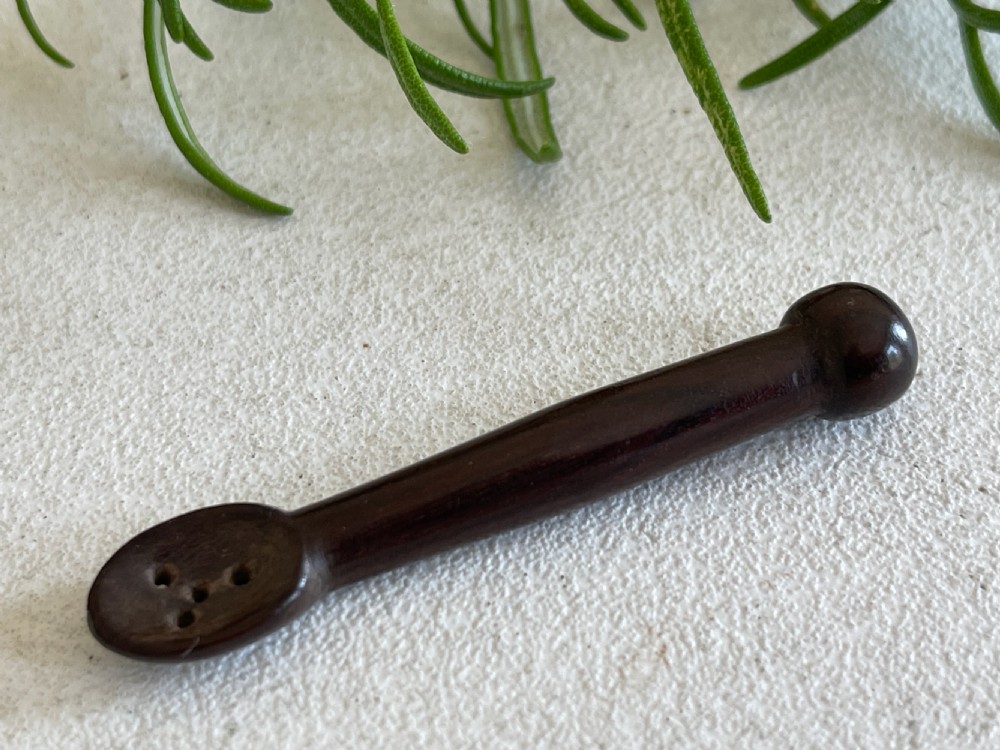 A dark carved wooden treen snuff spoon featuring a pierced bowl and a turned rounded terminal. View III