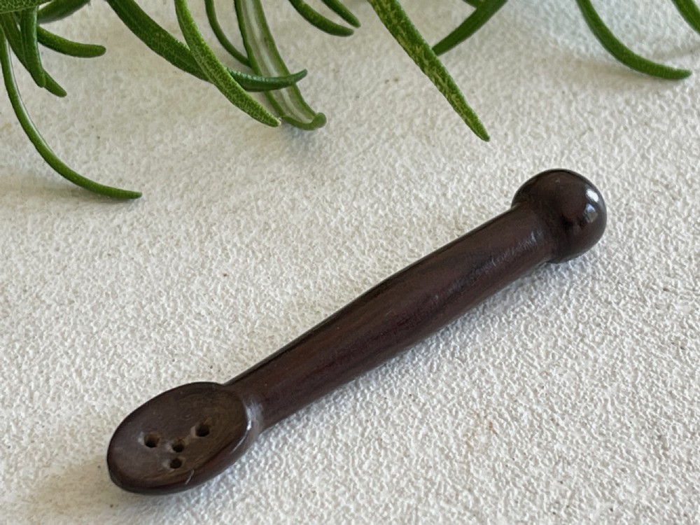 A dark carved wooden treen snuff spoon featuring a pierced bowl and a turned rounded terminal. View IV