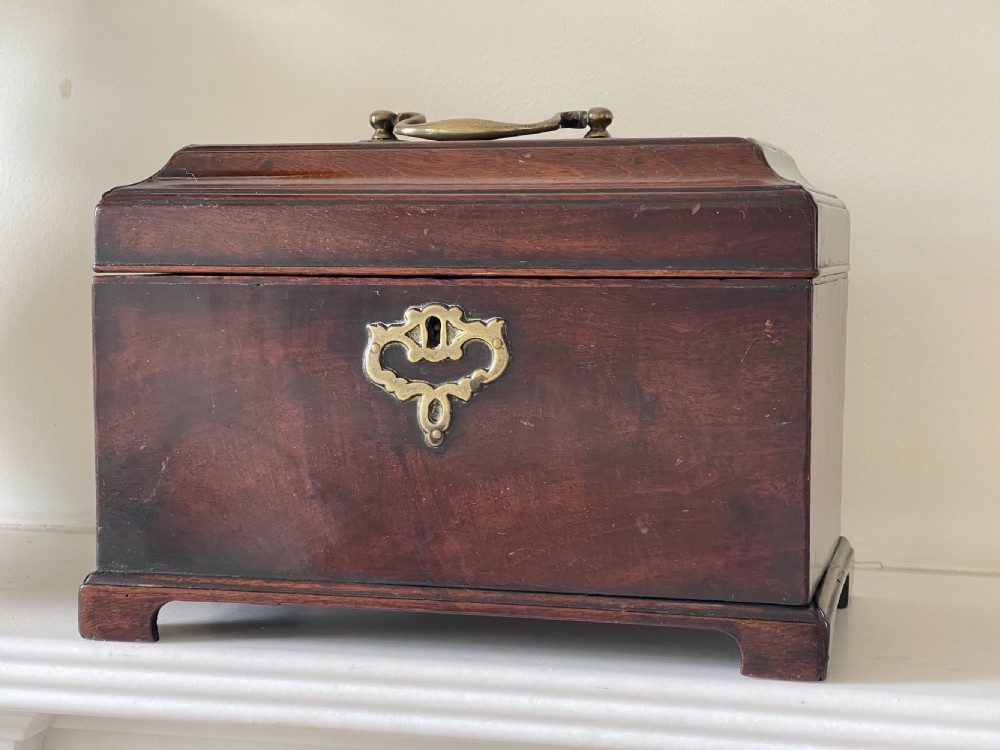 A rectangular dark mahogany tea caddy featuring a brass carrying handle on the lid and an ornate brass keyhole escutcheon on the front.