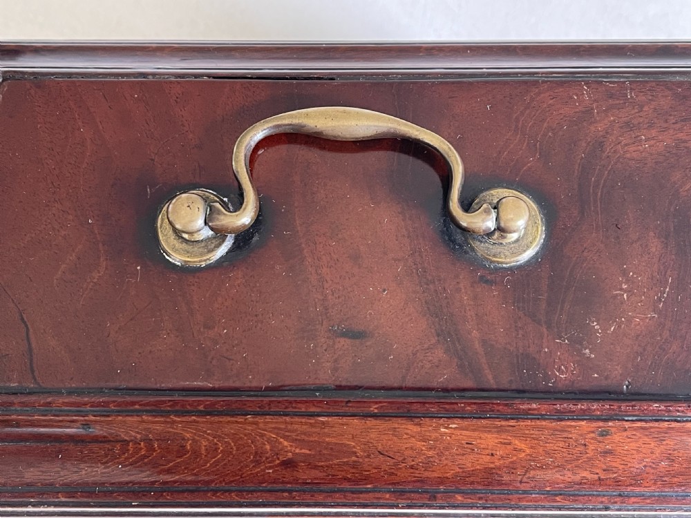 A rectangular dark mahogany tea caddy featuring a brass carrying handle on the lid and an ornate brass keyhole escutcheon on the front. View V