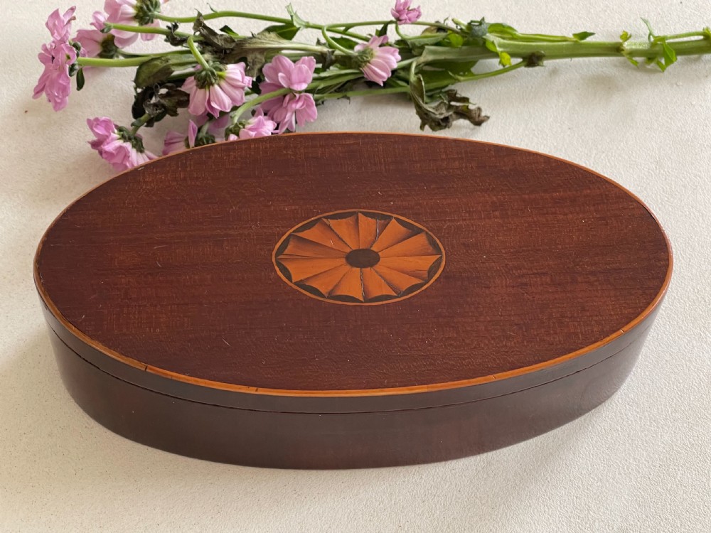 An oval dark mahogany wooden box featuring a central inlaid fan patera motif and subtle wood edging. View II