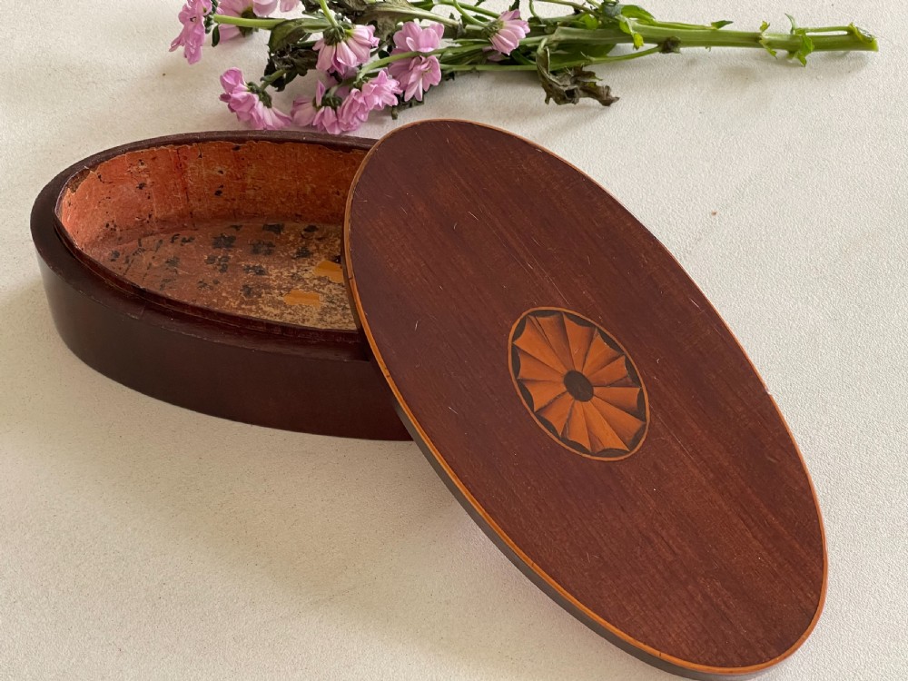 An oval dark mahogany wooden box featuring a central inlaid fan patera motif and subtle wood edging. View III