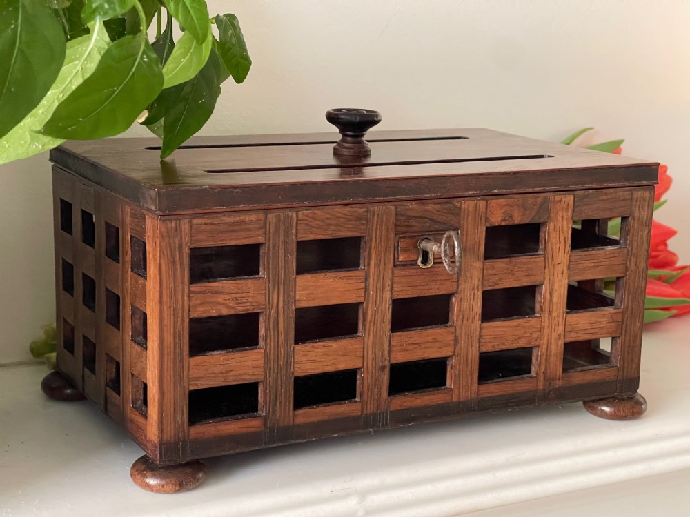 A rectangular antique rosewood stationery box featuring an open lattice exterior, a top lifting knob, bun feet, and an integrated key in the lock. View V